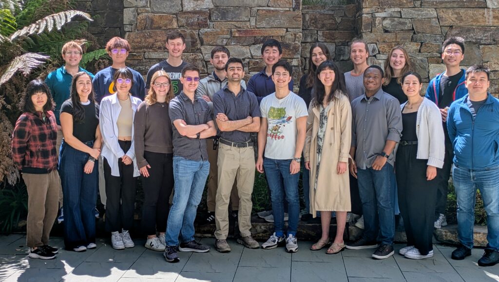 Group picture of the 2024 first-year graduate students standing against a brick wall.